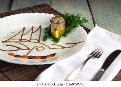 mackerel on a white dish with a pattern of soy sauce on a wooden background