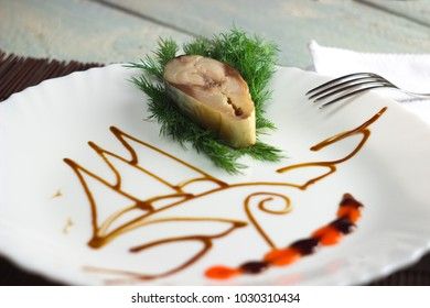 a piece of mackerel on a white dish with a pattern of soy sauce on a wooden background