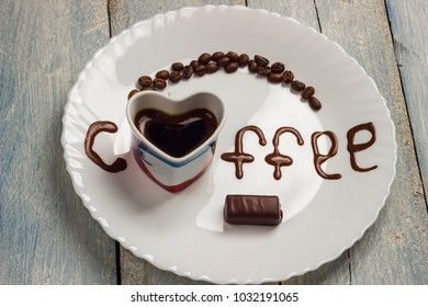black grain coffee with chocolate candy on a white plate with a wooden background and an inscription