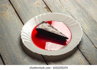 Chocolate decadence pie with strawberry jam on a wooden background