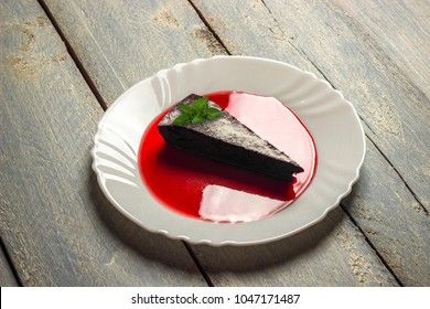 Chocolate decadence pie with mint and strawberry jam on a wooden background
