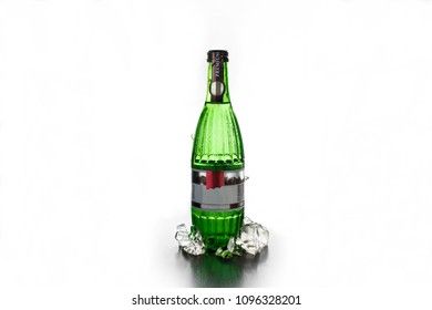 Glass green bottle of mineral water with ice on a white background