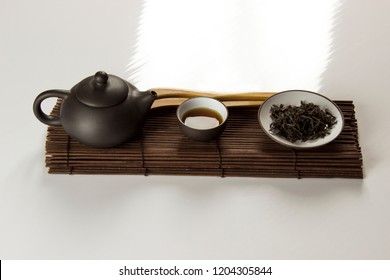 small clay teapot, tea and tea ceremony supplies on a white background 