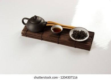 small clay teapot, tea and tea ceremony supplies on a white background