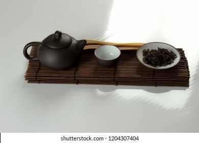 small clay teapot, tea and tea ceremony supplies on a white background