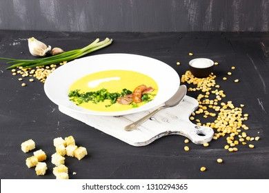 Pea soup with pieces of bacon, parsley and onion in a bowl on a dark background. Pea cream soup.
