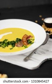 Pea soup with pieces of bacon, parsley and onion in a bowl on a dark background. Pea cream soup. Macro
