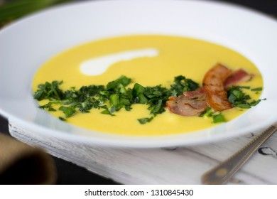 Pea soup with pieces of bacon, parsley and onion in a bowl on a dark background. Pea cream soup. Macro.