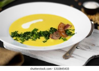 Pea soup with pieces of bacon, parsley and onion in a bowl on a dark background. Pea cream soup. Macro.