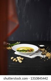 Pea soup with pieces of bacon, parsley and onion in a bowl on a dark background. Pea cream soup. with a curtain