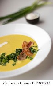 Pea soup with pieces of bacon, parsley and onion in a bowl on a white background macro. Pea cream soup.