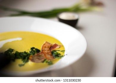 Pea soup with pieces of bacon, parsley and onion in a bowl on a white background macro. Pea cream soup.