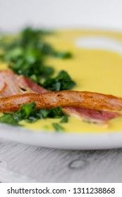 Pea soup with pieces of bacon, parsley and onion in a bowl on a dark background. Pea cream soup. Macro.
