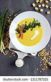 Pea soup with bacon and croutons on a gray background, top view. Yellow cream soup puree with greens.