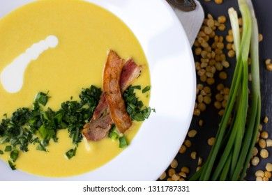 Pea soup with pieces of bacon, parsley and onion in a bowl on a dark background. Pea cream soup.