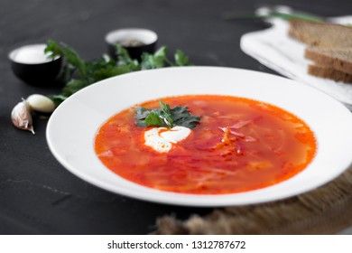 Traditional Ukrainian Russian borsch with sour cream and white beans on a dark background. Red vegetable beetroot soup.