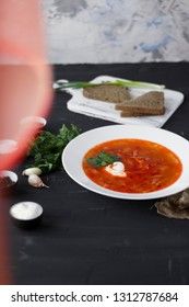 Traditional Ukrainian Russian borsch with sour cream and white beans on a dark background. Red vegetable beetroot soup.