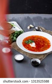 Traditional Ukrainian Russian borsch with sour cream and white beans on a dark background. Red vegetable beetroot soup.