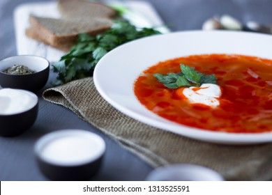 Traditional Ukrainian Russian borsch with sour cream and white beans on a gray background, view from above. Red vegetable beetroot soup.