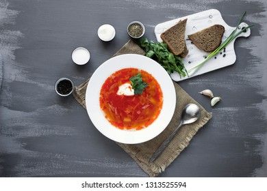 Traditional Ukrainian Russian borsch with sour cream and white beans on a gray background, view from above. Red vegetable beetroot soup.