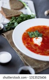 Traditional Ukrainian Russian borsch with sour cream and white beans on a dark background, macro. Red vegetable beetroot soup.