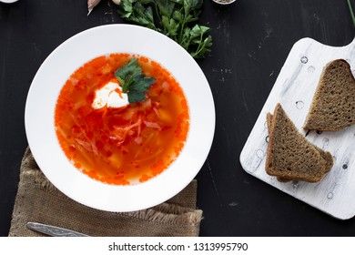 Traditional Ukrainian Russian borsch with sour cream and white beans on a dark background, view from above. Red vegetable beetroot soup.