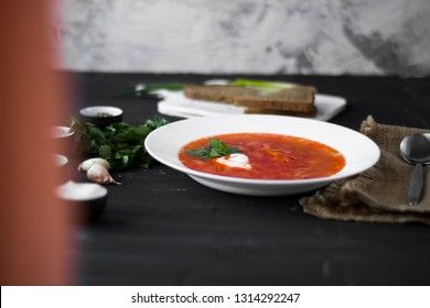 Traditional Ukrainian Russian borsch with sour cream and white beans on a dark background. Red vegetable beetroot soup.