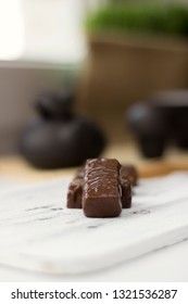 chocolate candies on clay teapot background