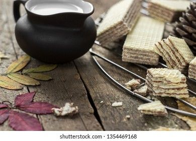 Sweet russian artek waffles on wooden background, with a pot of milk. Traditional sweets and dessert.