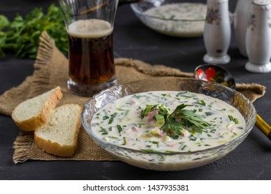 Cold Soup Okroshka. With sausage, vegetables and kvass serving size in bowl and raw ingredients on wooden table