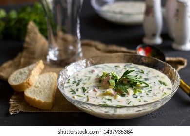 Cold Soup Okroshka. With sausage, vegetables and kvass serving size in bowl and raw ingredients on wooden table