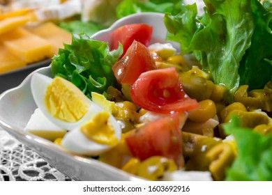 Greek salad with olives, tomatoes, feta cheese, onions in blue bowl on wooden background. Close up. Selective focus.