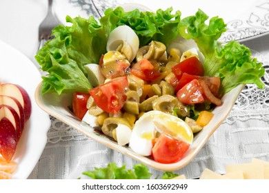 Greek salad with olives, tomatoes, feta cheese, onions in blue bowl on wooden background. Close up. Selective focus.