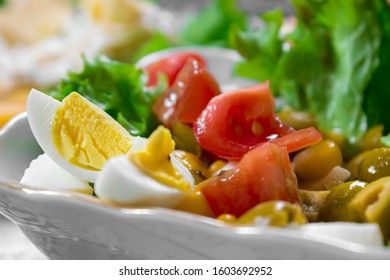 Greek salad with olives, tomatoes, feta cheese, onions in blue bowl on wooden background. Close up. Selective focus.