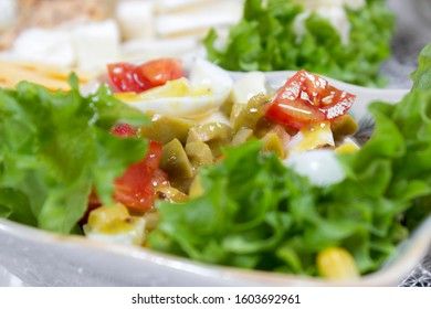 Greek salad with olives, tomatoes, feta cheese, onions in blue bowl on wooden background. Close up. Selective focus.