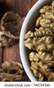 Peeled walnut in a white cup on a wooden background